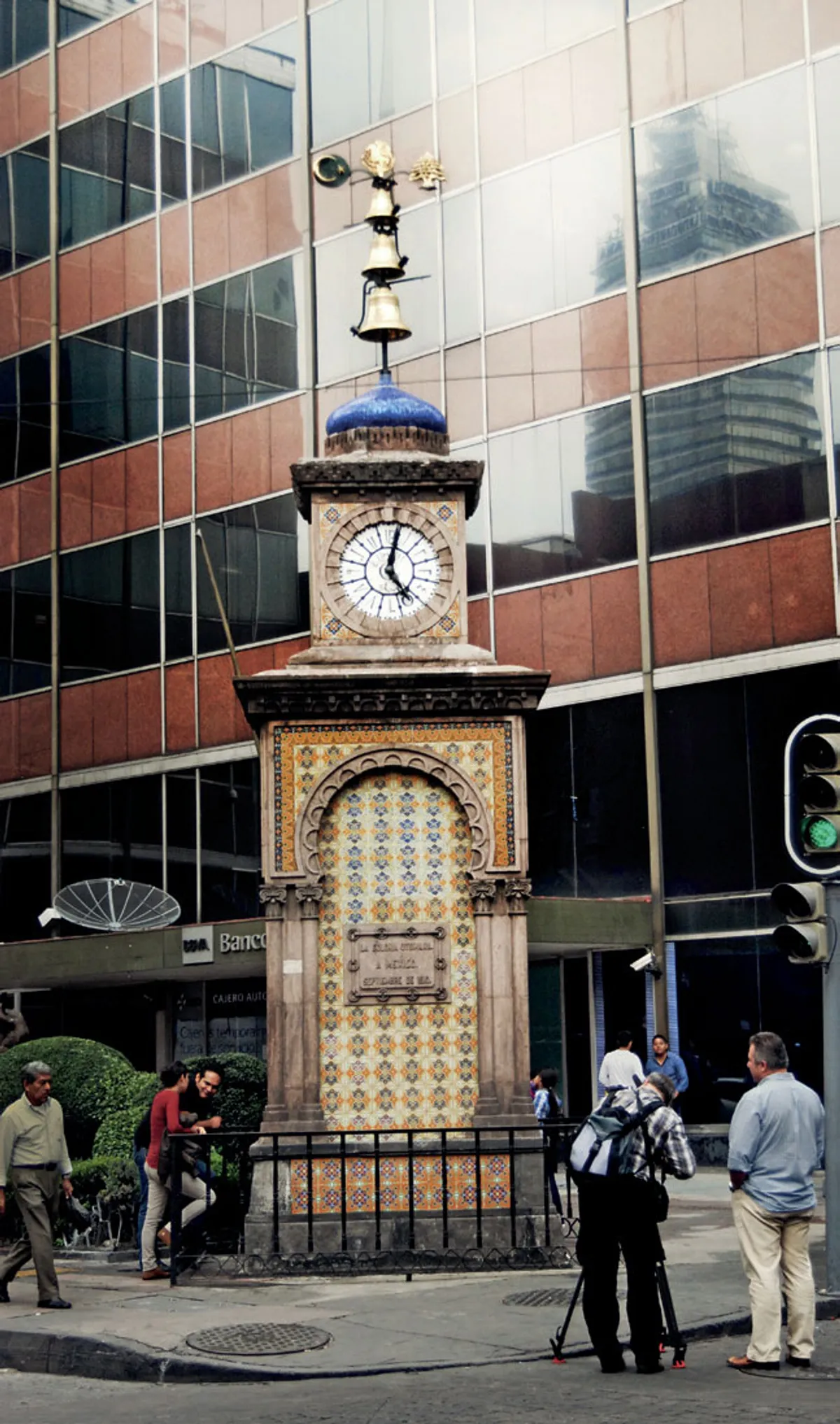 An ornate wrought-iron clock tower with tiled top, a gift from the Ottoman community to Mexico City, standing on a street corner.