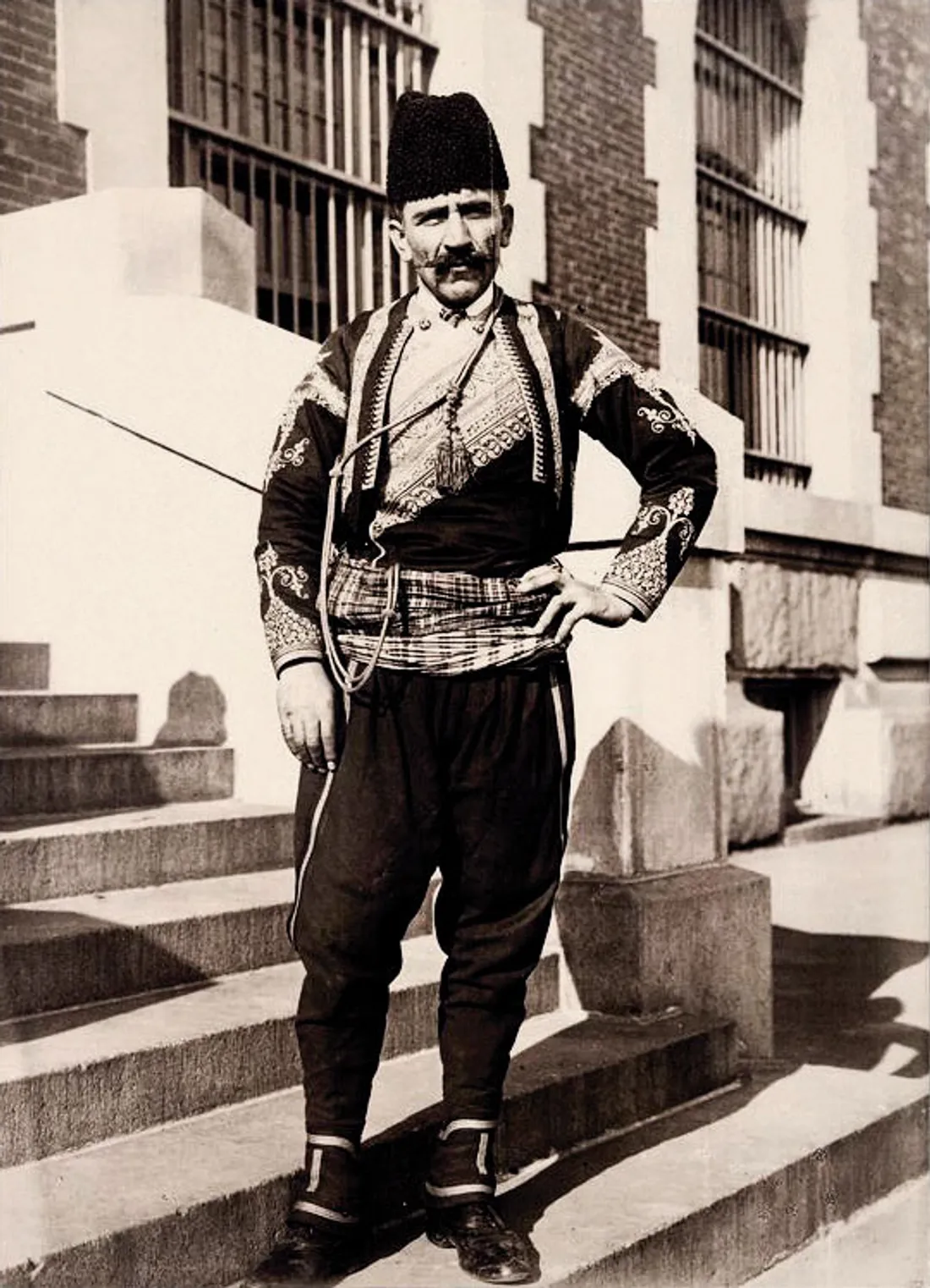 A black-and-white photograph of a Turkish immigrant in traditional Ottoman dress on a New York street in 1912.