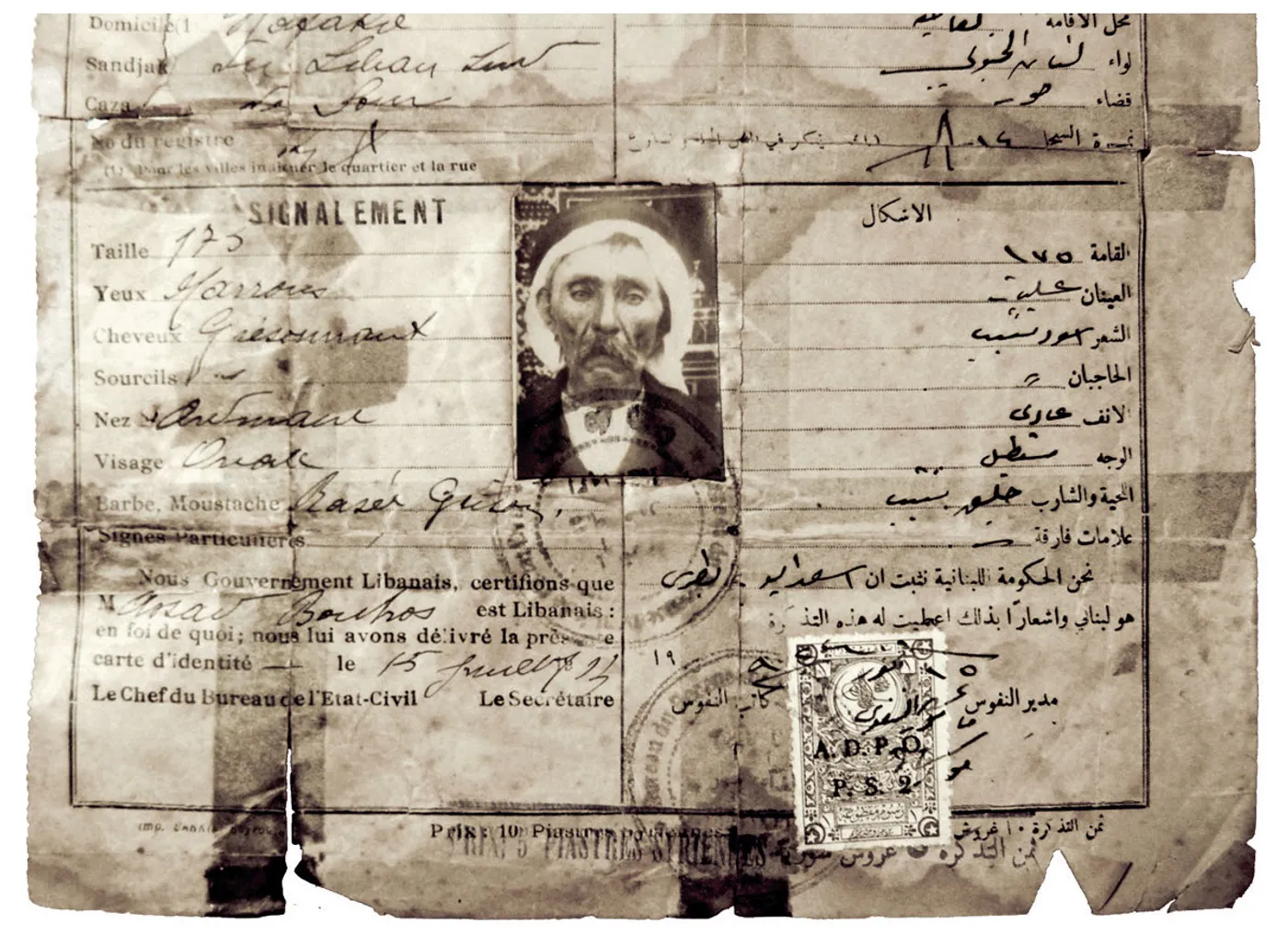 An Ottoman-era passport booklet lying open, with handwritten entries in Ottoman Turkish and a red-inked consular stamp.