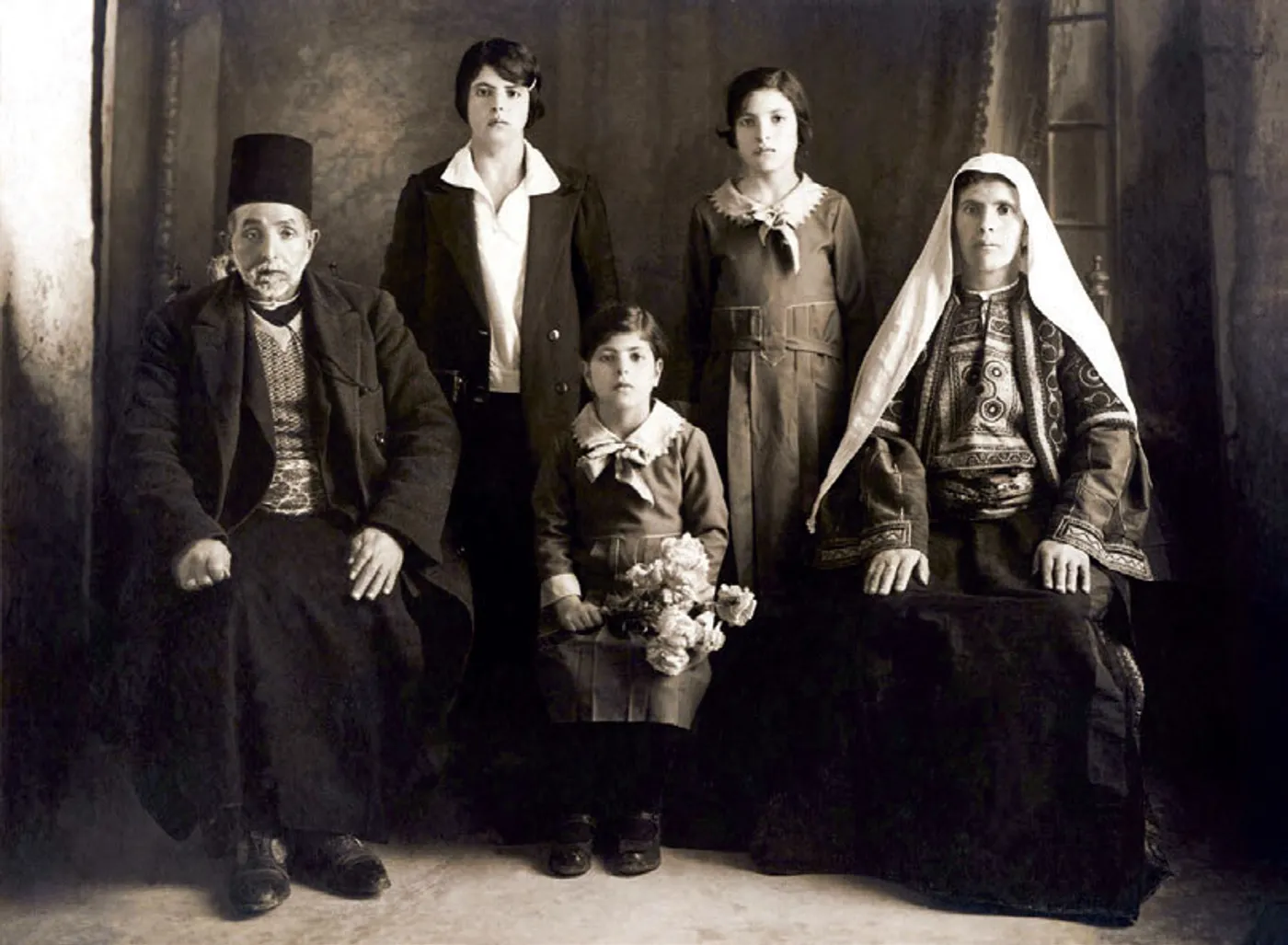 A sepia-toned family portrait of a Palestinian family in formal clothing, photographed in a studio after their arrival in Chile.