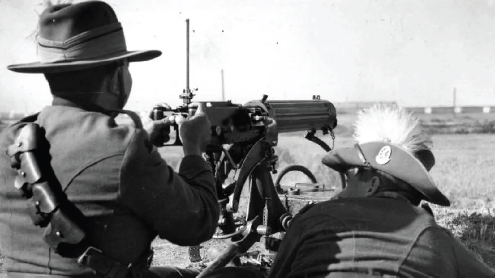 Soldiers in the field aiming and firing a Lewis machine gun mounted low to the ground during the emu hunt.